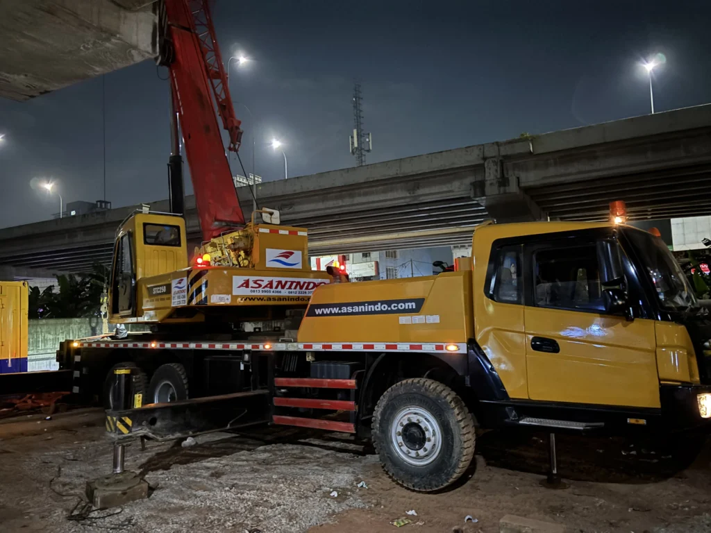 Outrigger hidrolik mobile crane dalam posisi terbentang penuh mengangkat chassis dari tanah untuk memberikan stabilitas maksimal saat operasional lifting